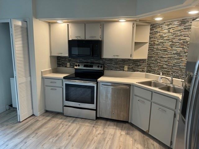 kitchen with sink, tasteful backsplash, light hardwood / wood-style flooring, and appliances with stainless steel finishes