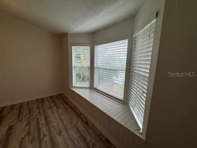 unfurnished room with a textured ceiling and dark hardwood / wood-style floors