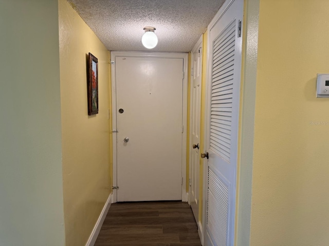 hallway with dark hardwood / wood-style floors and a textured ceiling