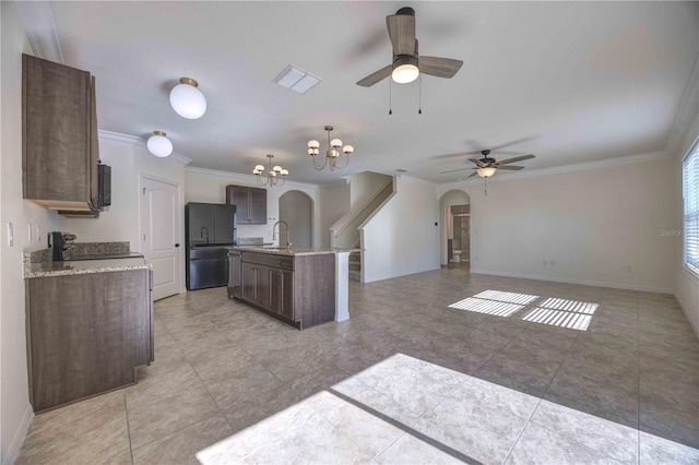 kitchen featuring ceiling fan with notable chandelier, pendant lighting, black fridge, a kitchen island with sink, and stove