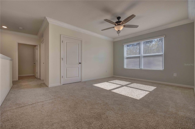 carpeted spare room with ceiling fan and crown molding