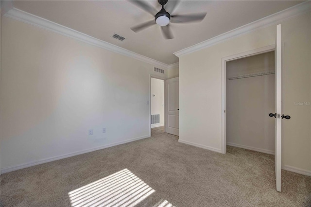 unfurnished bedroom featuring ceiling fan, crown molding, light colored carpet, and a closet