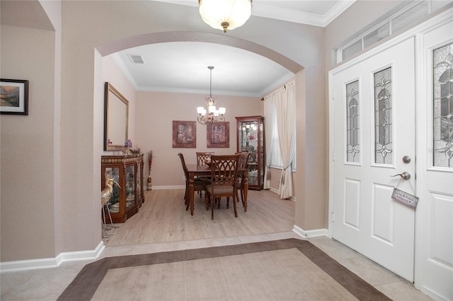 foyer entrance with light tile patterned floors, crown molding, and an inviting chandelier