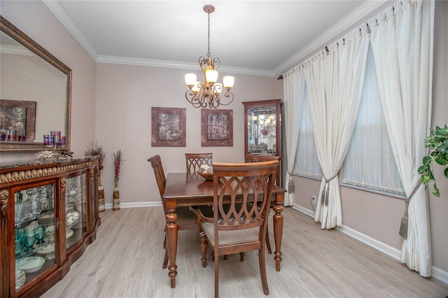 dining room featuring light wood-type flooring, ornamental molding, and an inviting chandelier