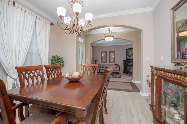 dining room with a fireplace, an inviting chandelier, and ornamental molding