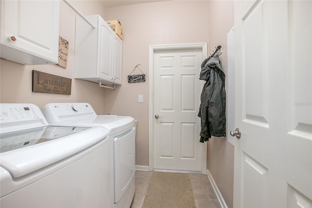 washroom with light tile patterned floors, washing machine and clothes dryer, and cabinets