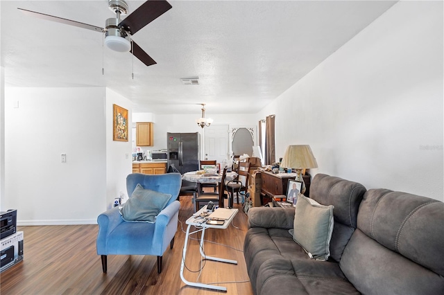 living room featuring ceiling fan with notable chandelier and hardwood / wood-style floors