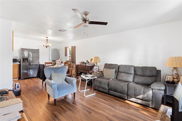 living room featuring ceiling fan with notable chandelier and wood-type flooring