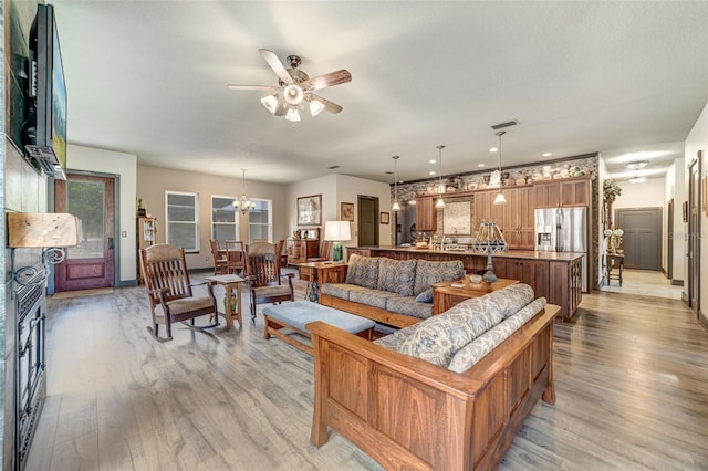 living room featuring light wood-type flooring and ceiling fan with notable chandelier