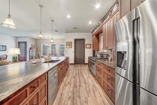 kitchen with pendant lighting, appliances with stainless steel finishes, light hardwood / wood-style floors, sink, and backsplash