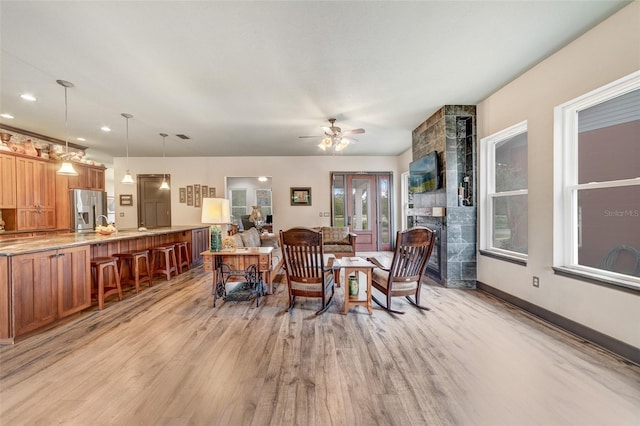 dining room with ceiling fan, light hardwood / wood-style flooring, and a fireplace