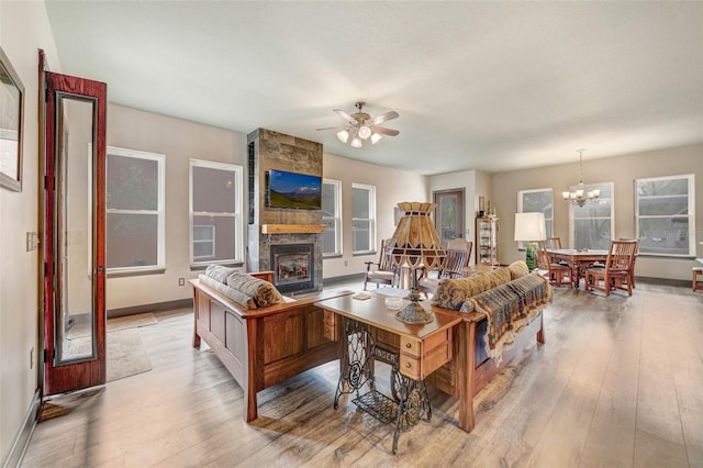 living room featuring ceiling fan with notable chandelier, light hardwood / wood-style flooring, and a fireplace