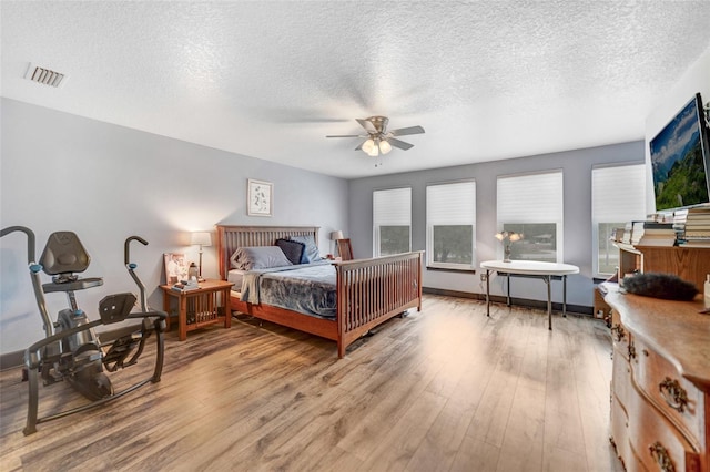 bedroom with ceiling fan, a textured ceiling, and light wood-type flooring