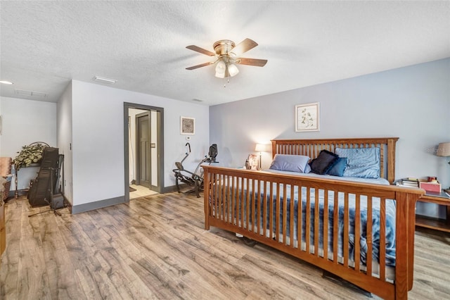 bedroom with a textured ceiling, ceiling fan, and light hardwood / wood-style flooring