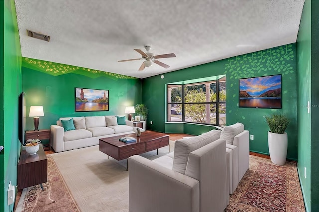 living room featuring ceiling fan, wood-type flooring, and a textured ceiling