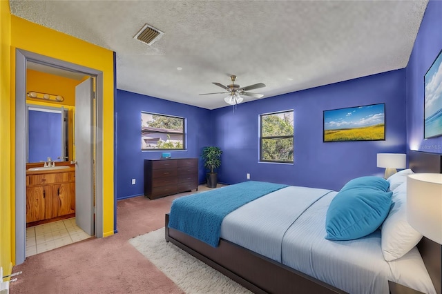 bedroom with light carpet, connected bathroom, multiple windows, and ceiling fan