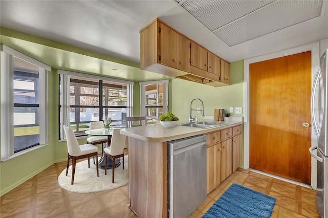 kitchen with stainless steel appliances, light brown cabinetry, kitchen peninsula, and sink