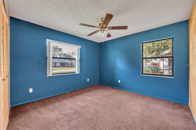 spare room featuring ceiling fan, carpet, and a textured ceiling