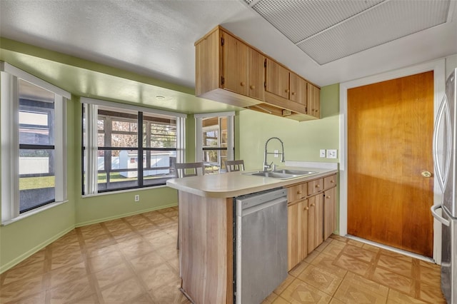 kitchen with sink, plenty of natural light, kitchen peninsula, and appliances with stainless steel finishes