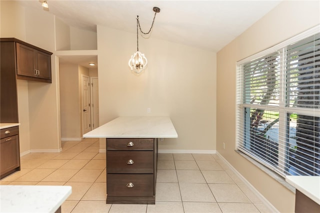 interior space with pendant lighting, light tile patterned floors, vaulted ceiling, and kitchen peninsula