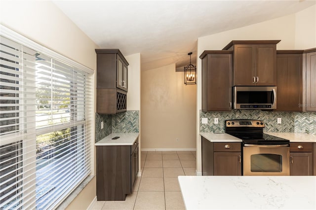 kitchen with pendant lighting, lofted ceiling, appliances with stainless steel finishes, and light tile patterned flooring