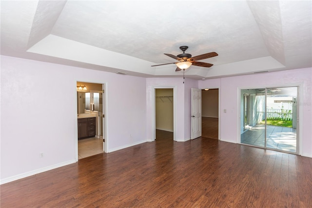 spare room with ceiling fan, dark hardwood / wood-style flooring, and a tray ceiling