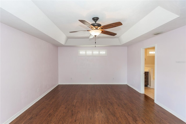 spare room with dark wood-type flooring, ceiling fan, and a tray ceiling