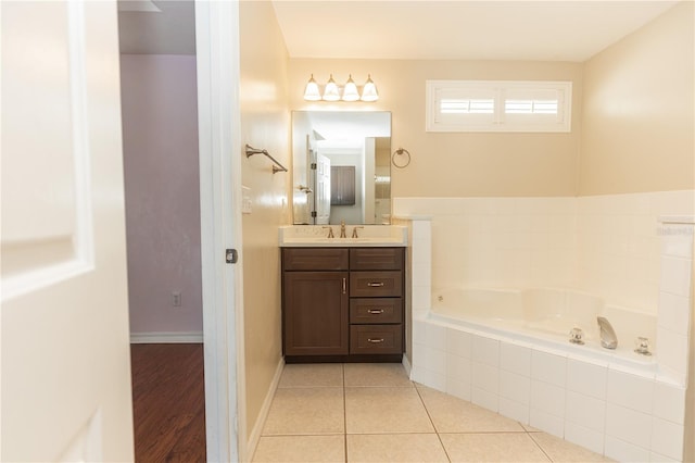 bathroom featuring tile patterned flooring, vanity, and tiled tub