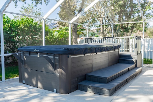 exterior space with a hot tub, a patio area, and glass enclosure