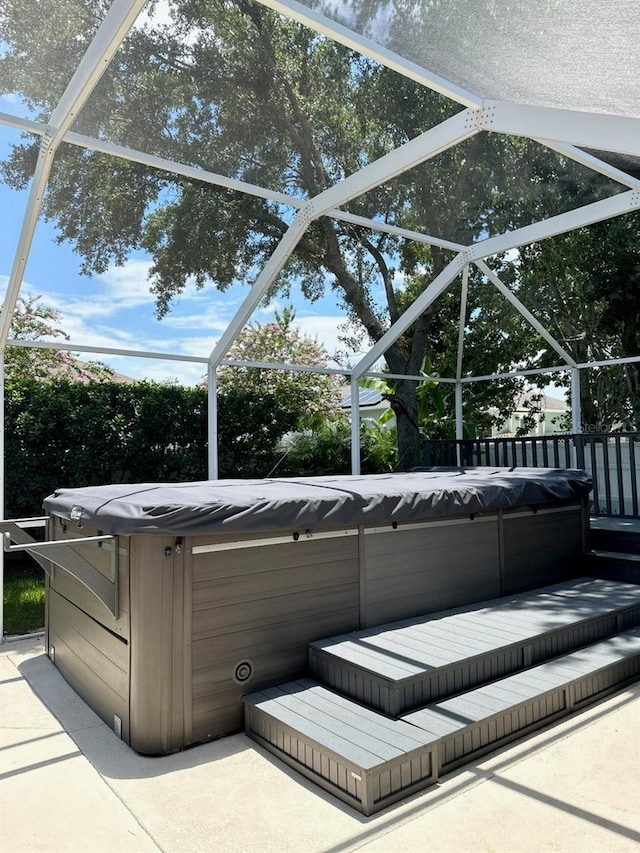 view of patio / terrace with a hot tub and glass enclosure