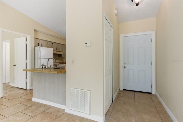 interior space featuring light tile patterned flooring, lofted ceiling, white fridge, and electric range