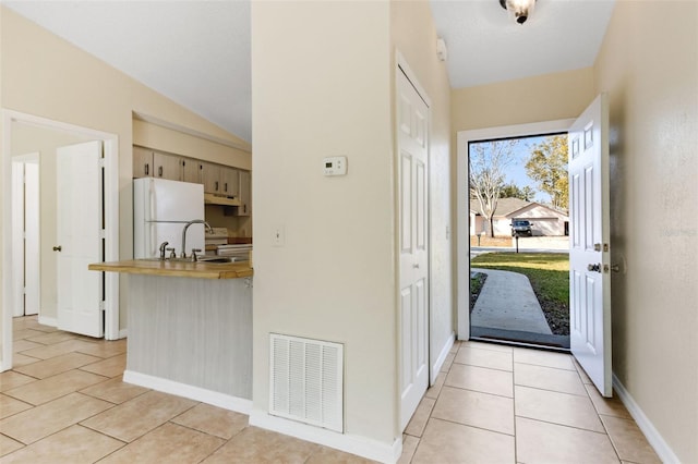 doorway featuring vaulted ceiling, sink, and light tile patterned floors