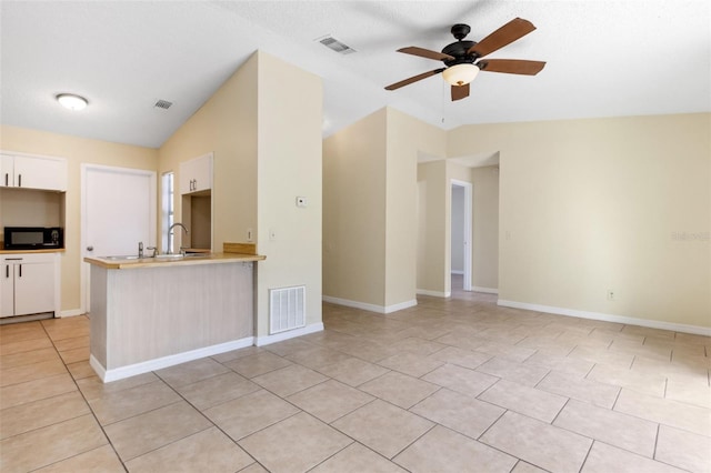 kitchen featuring lofted ceiling, light tile patterned floors, ceiling fan, white cabinets, and kitchen peninsula