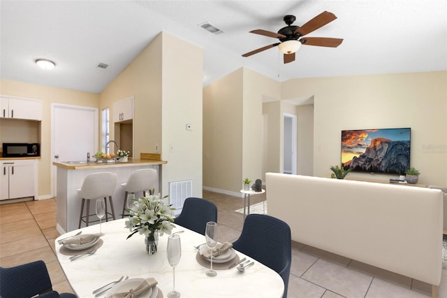 dining area with light tile patterned flooring, ceiling fan, and vaulted ceiling