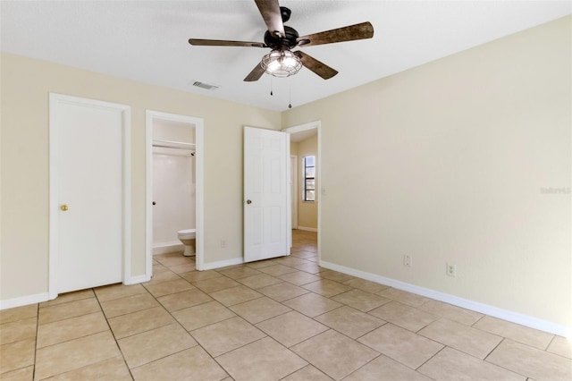 unfurnished bedroom with ensuite bathroom, light tile patterned floors, ceiling fan, and a closet