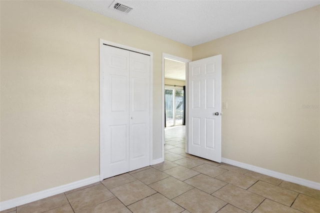 unfurnished bedroom featuring a closet and light tile patterned floors