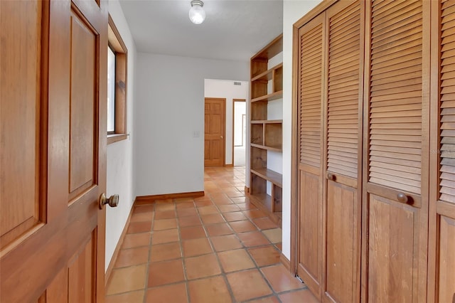 corridor featuring light tile patterned flooring and baseboards