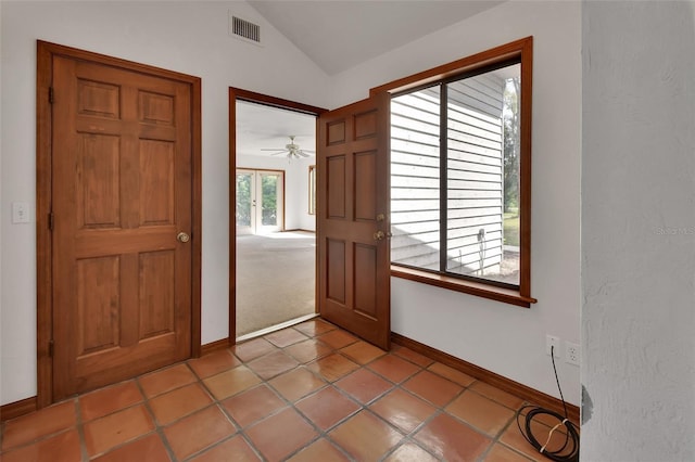 interior space featuring light tile patterned floors, visible vents, baseboards, and vaulted ceiling