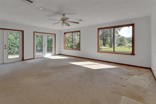 carpeted empty room with a wealth of natural light, visible vents, and french doors