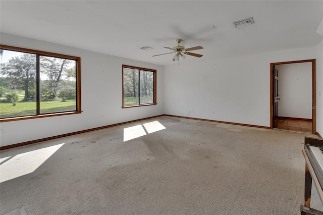 spare room with visible vents, light colored carpet, baseboards, and ceiling fan