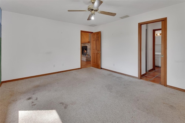 unfurnished room with visible vents, a fireplace, baseboards, and carpet floors