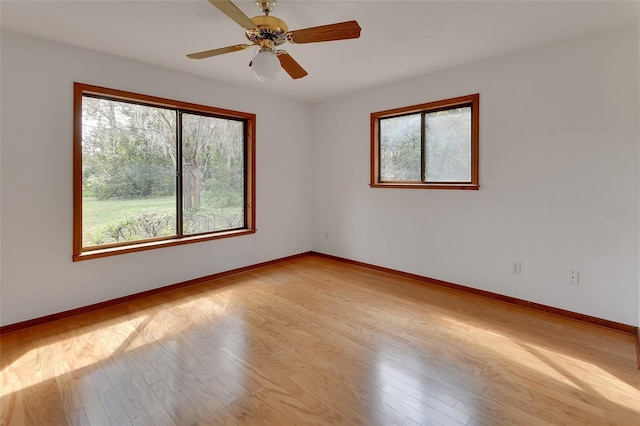 unfurnished room with light wood finished floors, a ceiling fan, and baseboards