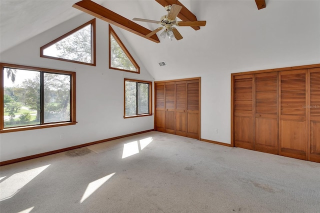 unfurnished bedroom with visible vents, baseboards, multiple closets, carpet flooring, and high vaulted ceiling