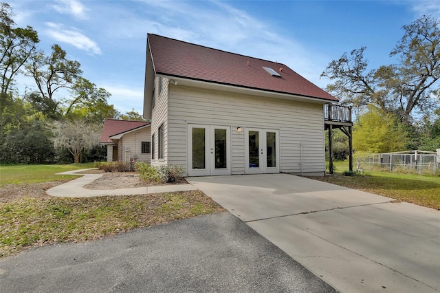 rear view of house featuring french doors, a shingled roof, and a deck