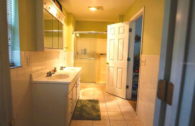 bathroom featuring tile patterned flooring, tile walls, a shower with shower door, and vanity