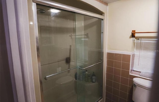 bathroom with toilet, tile walls, and an enclosed shower