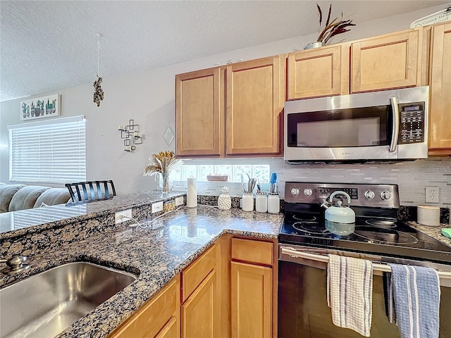 kitchen with appliances with stainless steel finishes, light brown cabinetry, sink, decorative backsplash, and a textured ceiling