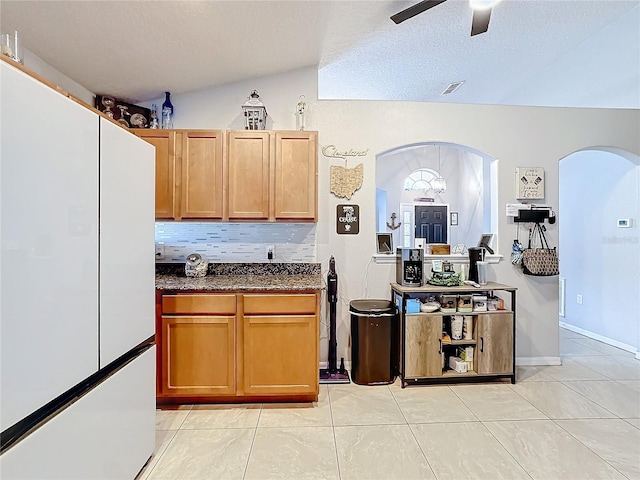 kitchen with lofted ceiling, backsplash, white refrigerator, ceiling fan, and a textured ceiling