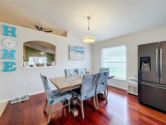 dining room featuring ceiling fan, lofted ceiling, dark hardwood / wood-style flooring, and a textured ceiling