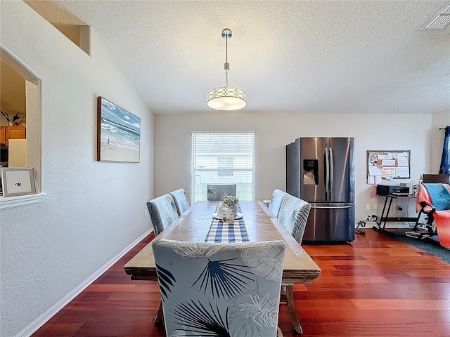 dining area featuring dark wood-type flooring and a textured ceiling